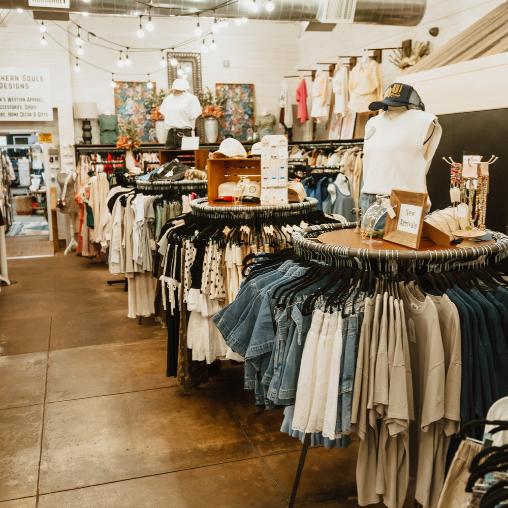 Interior of a clothing store with racks of clothes and mannequins.