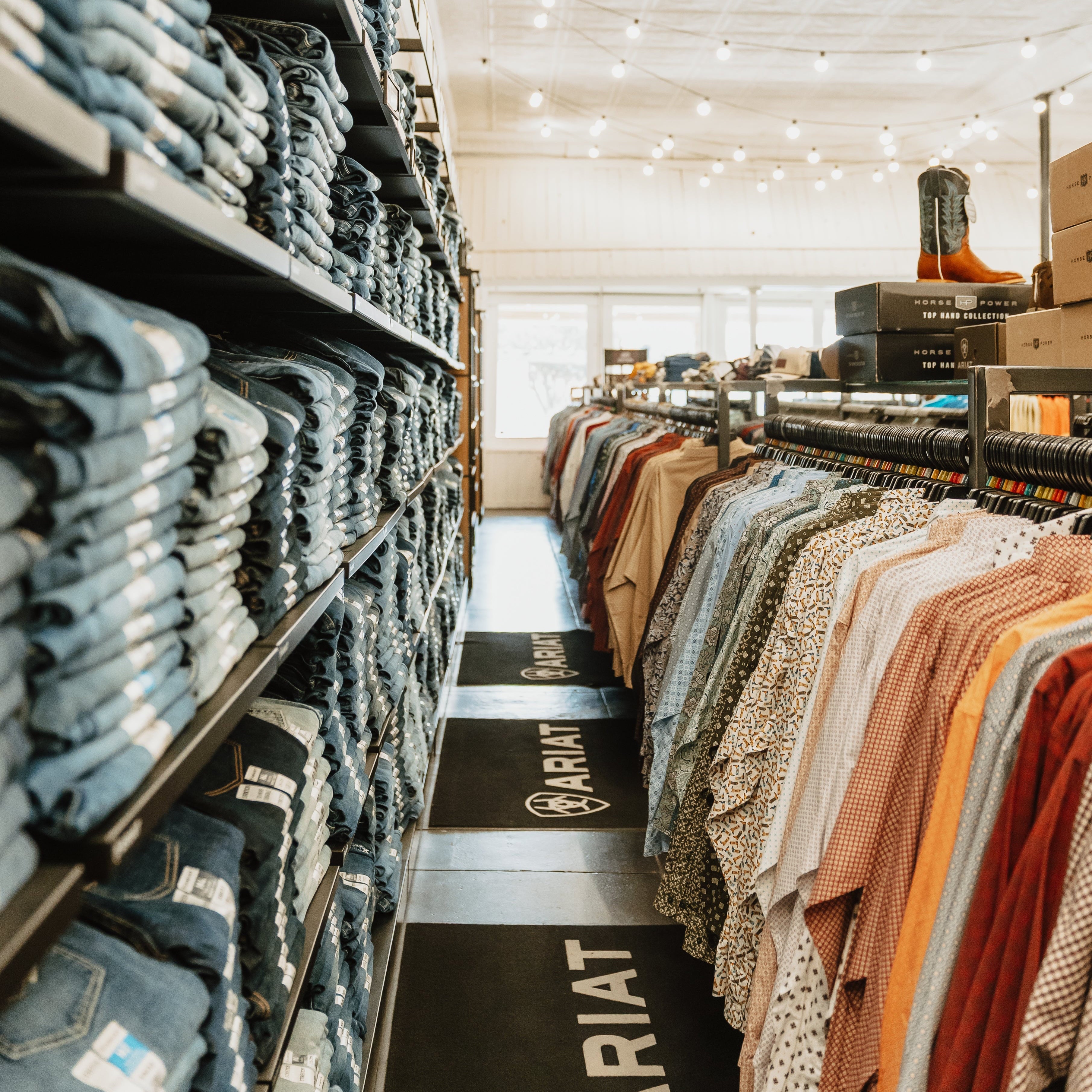 Clothing store interior with shelves of jeans and racks of clothes.